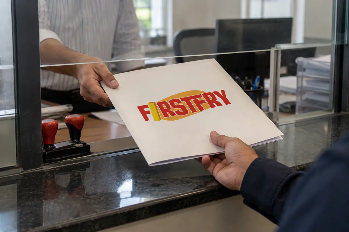 A FirstFry document folder being passed across an office counter