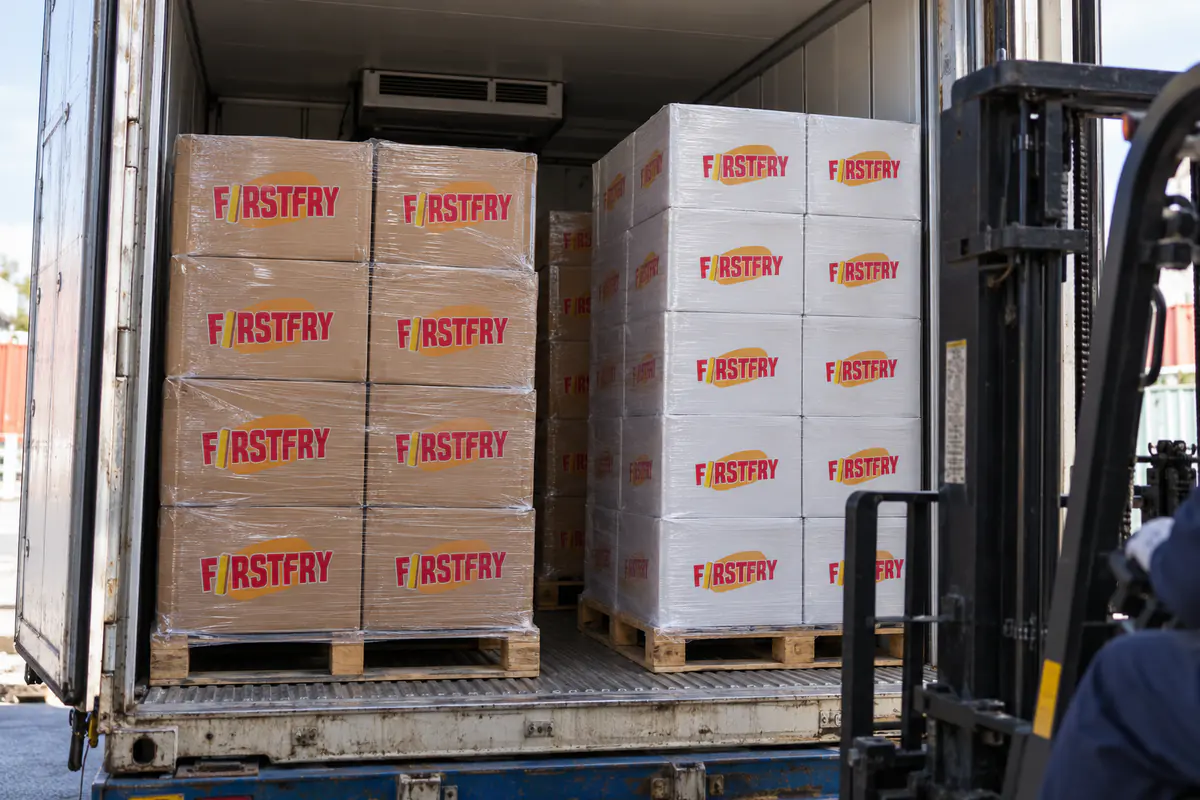Pallets of brown and white FirstFry cartons side by side inside a refrigerated container